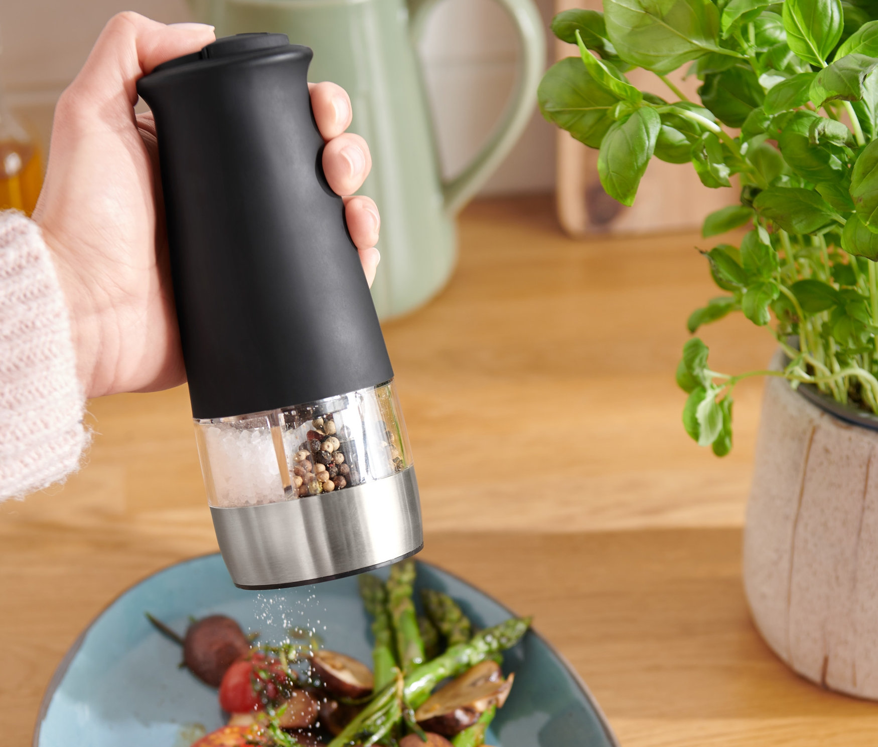 Osoba używa elektrycznego młynka do soli i pieprzu 2 w 1 na talerz z warzywami.