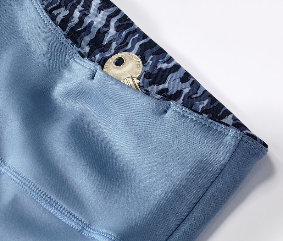 Szczegół dwustronnych legginsów sportowych w kolorze niebiesko-jasnoniebieskim z kluczem w kieszeni.