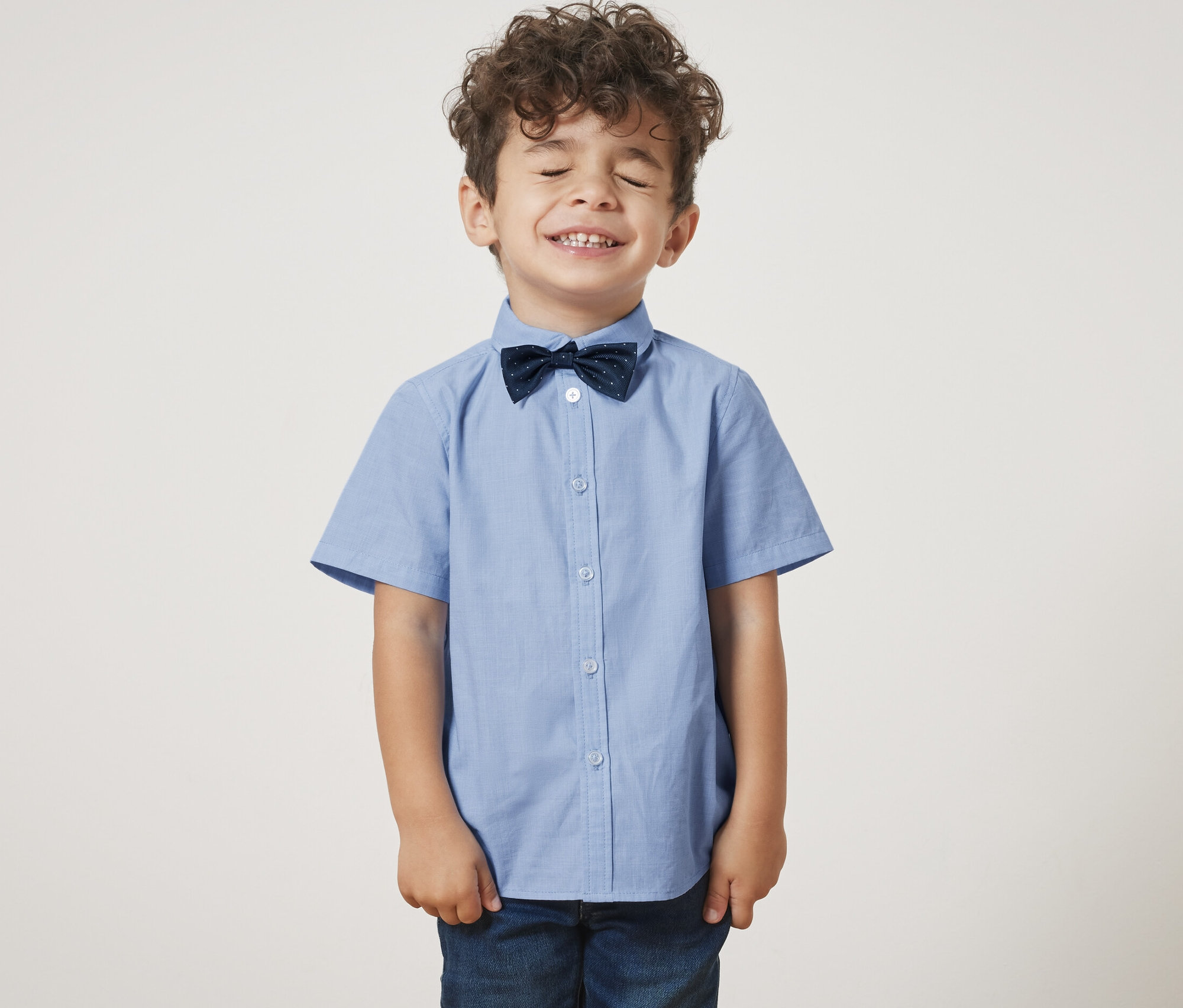 Chłopiec z zamkniętymi oczami ma na sobie koszulę z muszką.