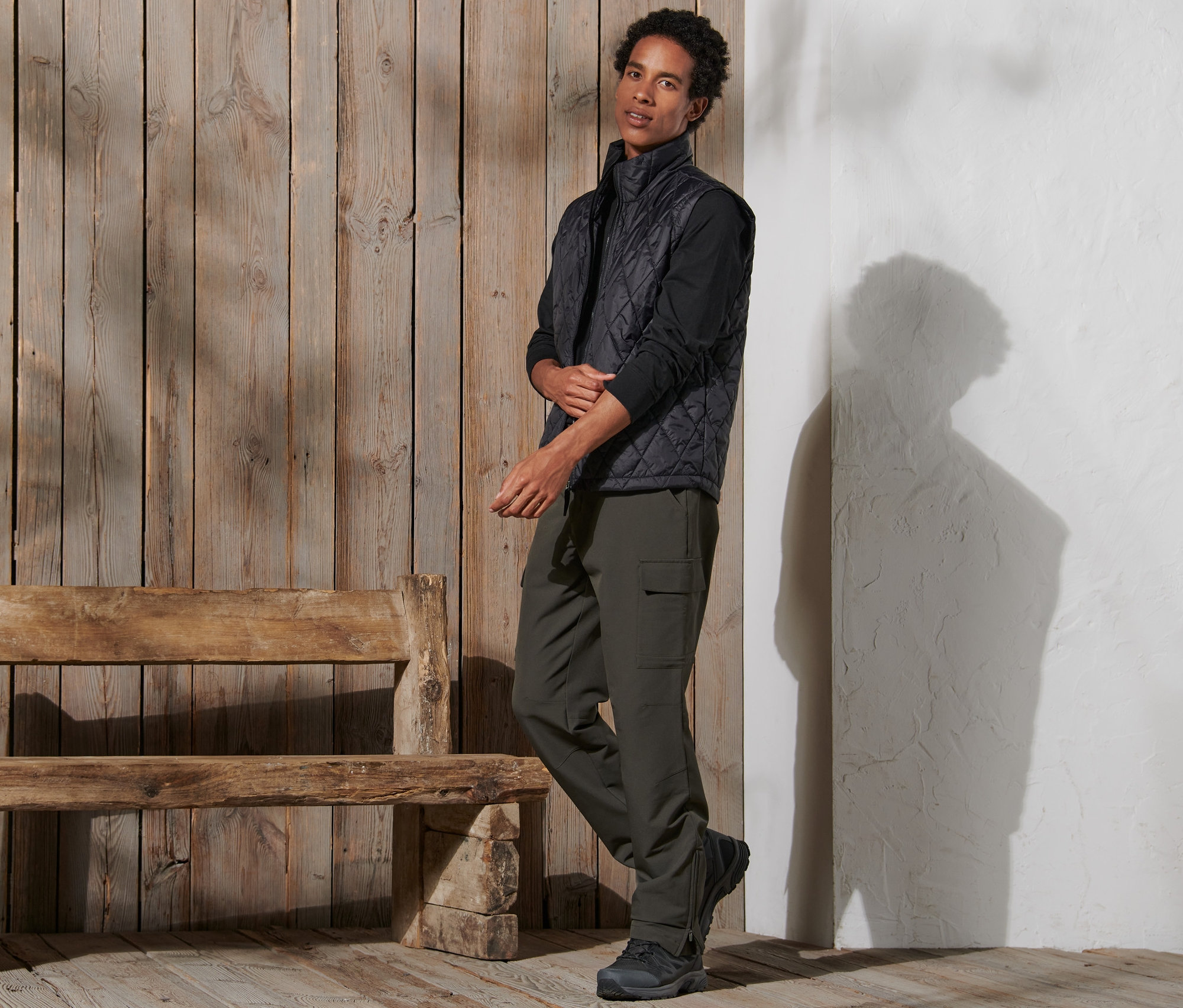 Mężczyzna stoi i ma na sobie spodnie termiczne, kamizelkę i buty.