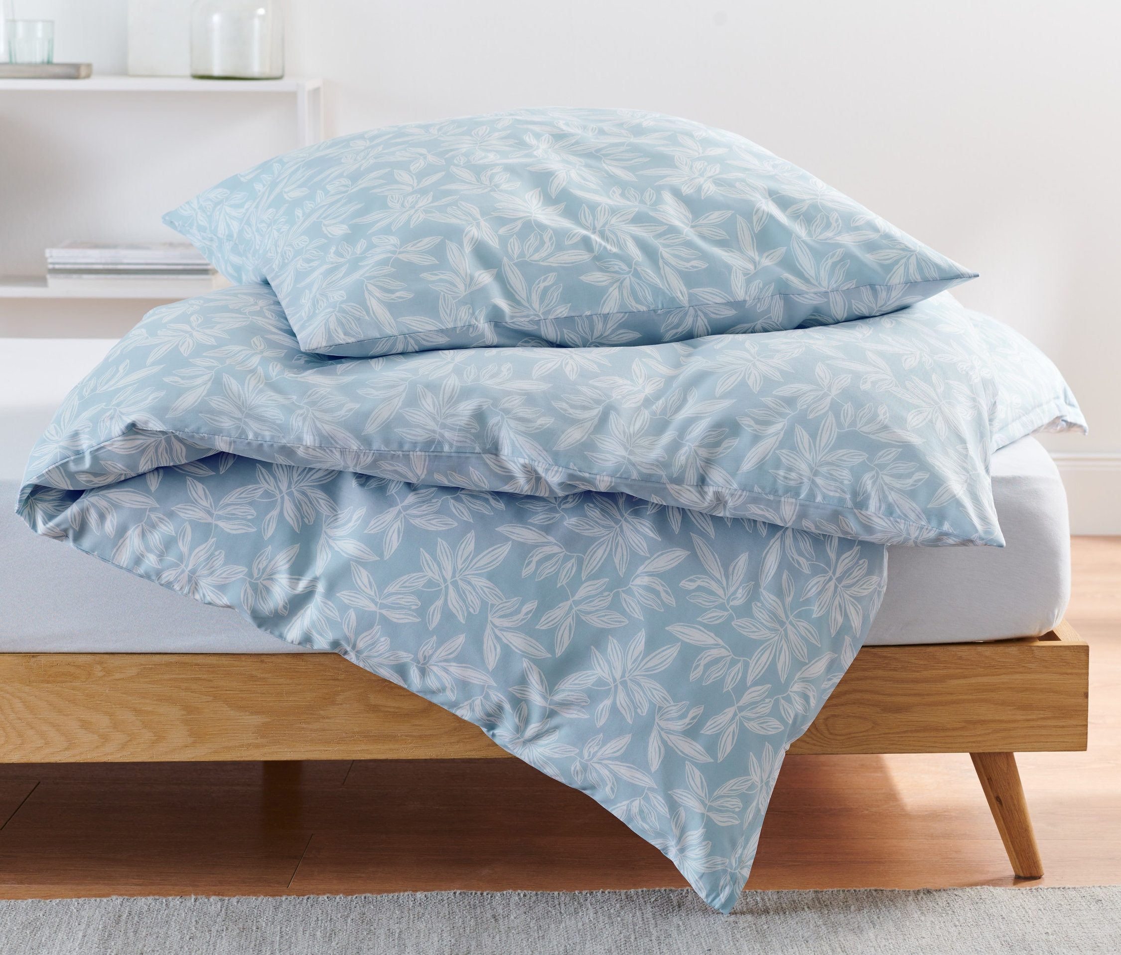 Na łóżku leży pościel bawełniana premium z motywem liści.