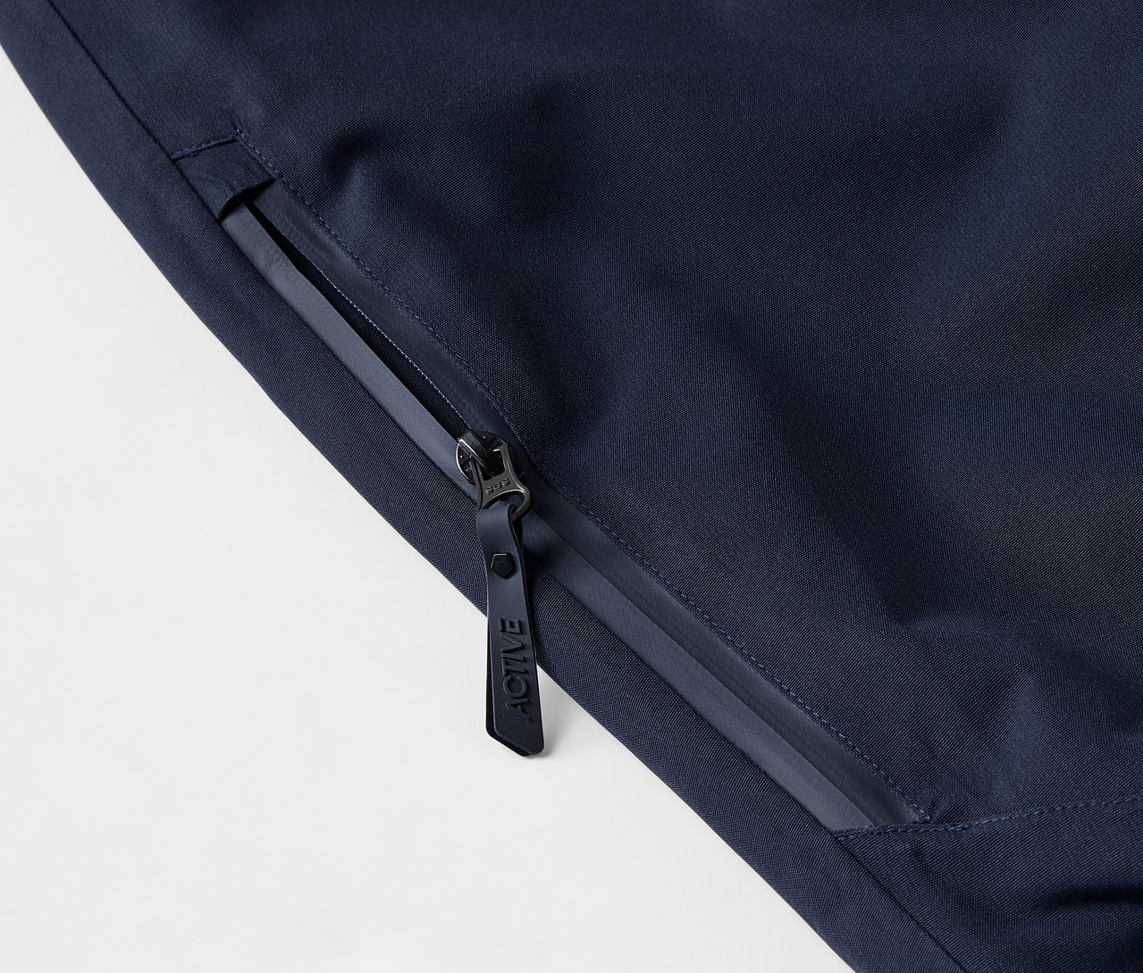 Zbliżenie na granatową kurtkę z zamkiem błyskawicznym i logo.