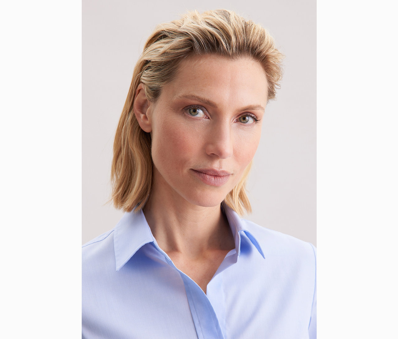 Kobieta ma na sobie jasnoniebieską bluzkę Seidensticker Slim Fit non iron.