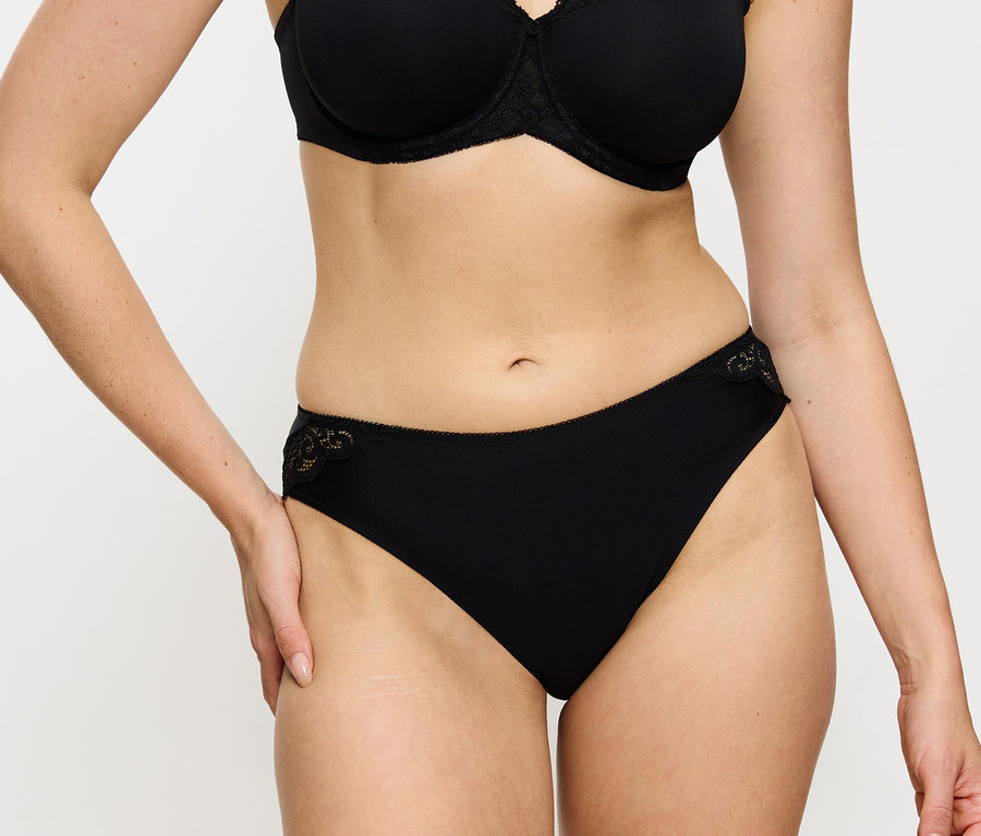 Kobieta nosi czarny biustonosz i figi Triumph Amourette Tai, black.