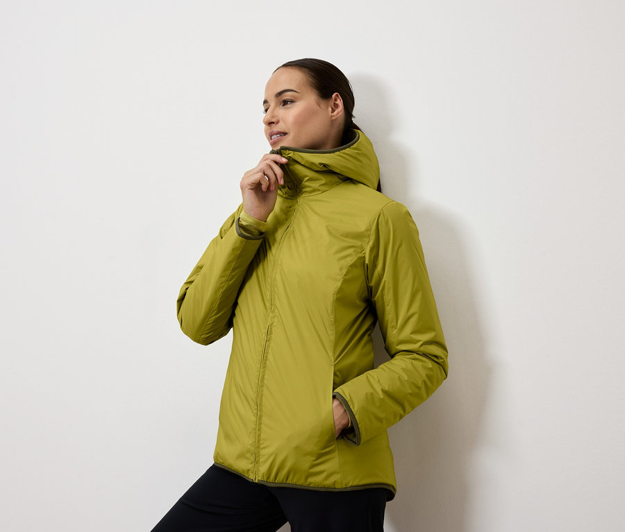 Kobieta zapina żółto-zieloną kurtkę z kapturem.