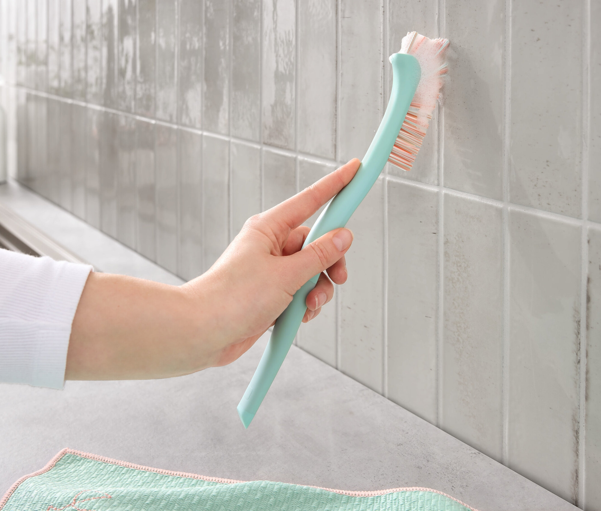 Ręka czyści szczotką do czyszczenia fug brudne fugi na płytkach.