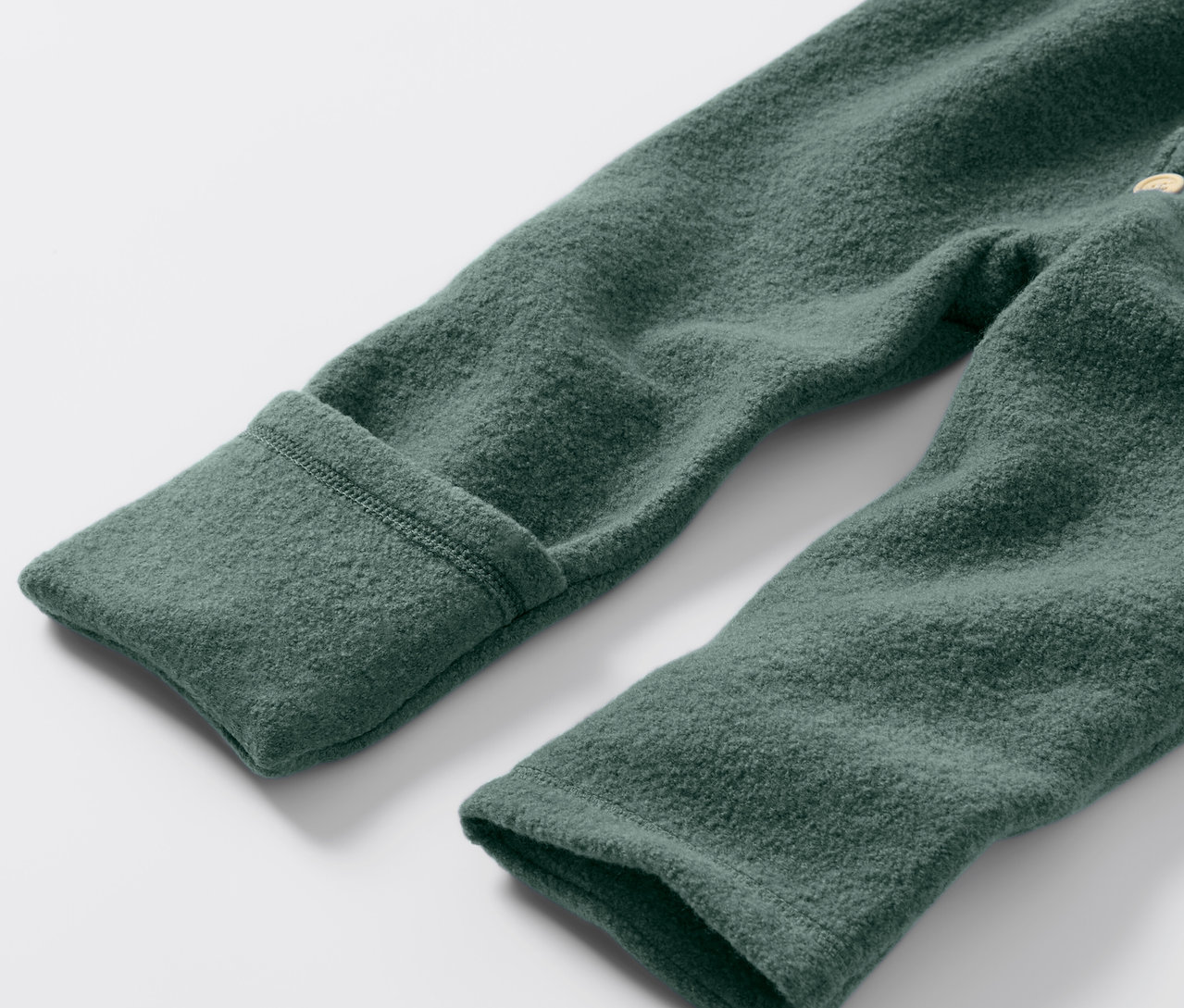 Zbliżenie na zielony kombinezon z wełny merino dla niemowląt.