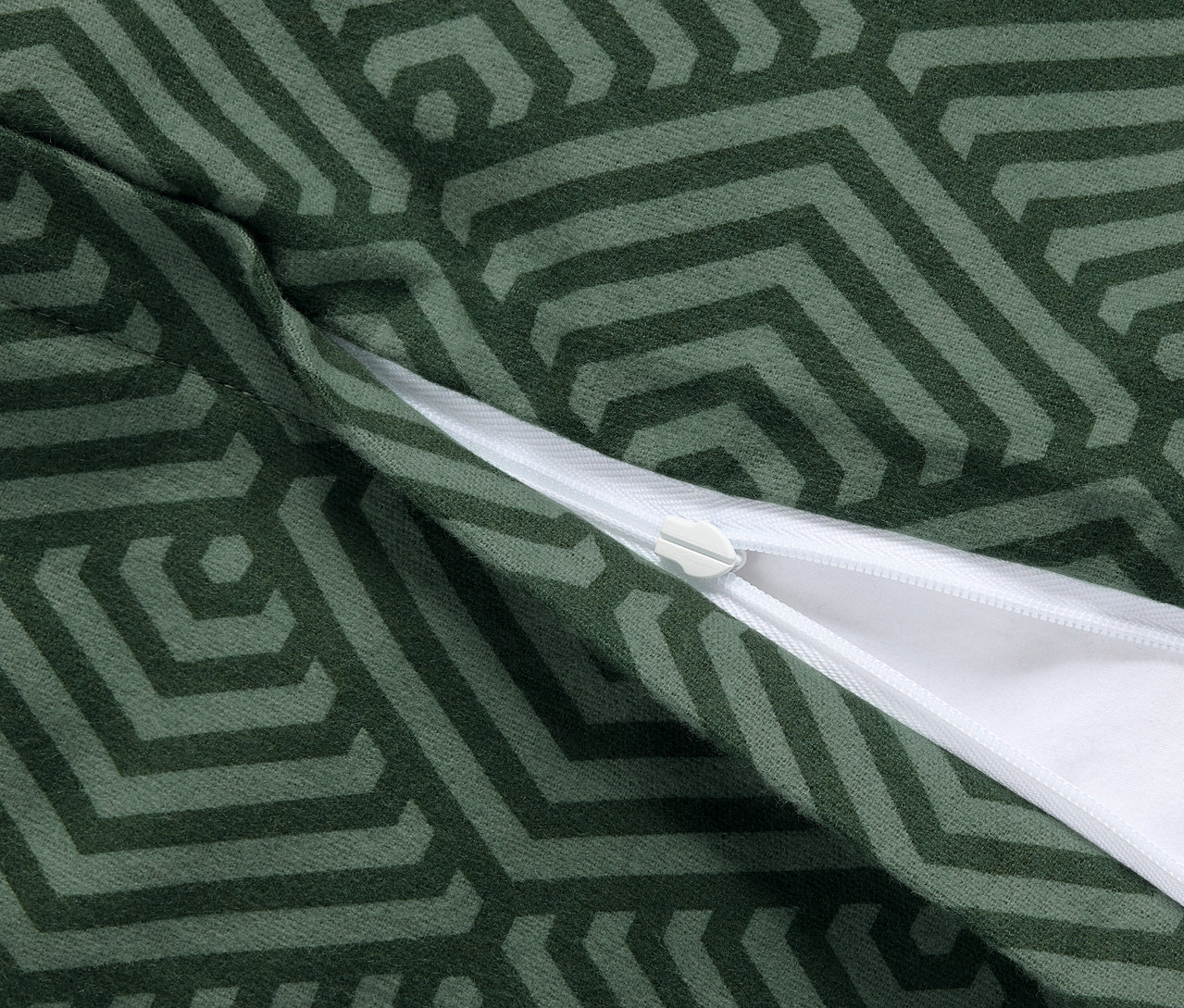 Zbliżenie na dwie zielone flanelowe poszewki na poduszki z geometrycznym wzorem i zamkiem błyskawicznym.