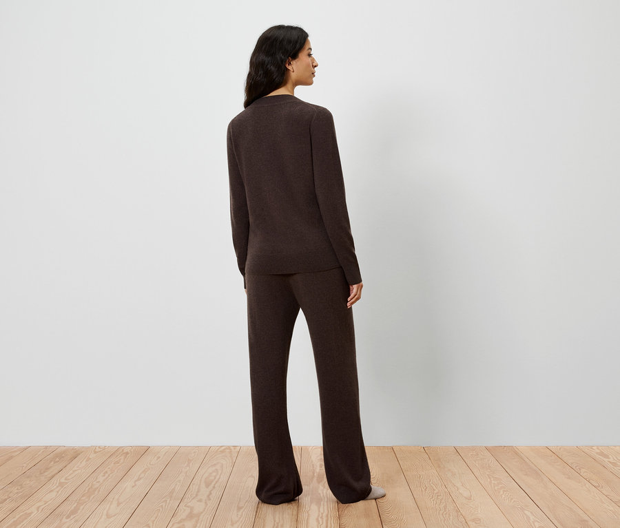 Widok z tyłu kobiety w brązowym swetrze i spodniach.