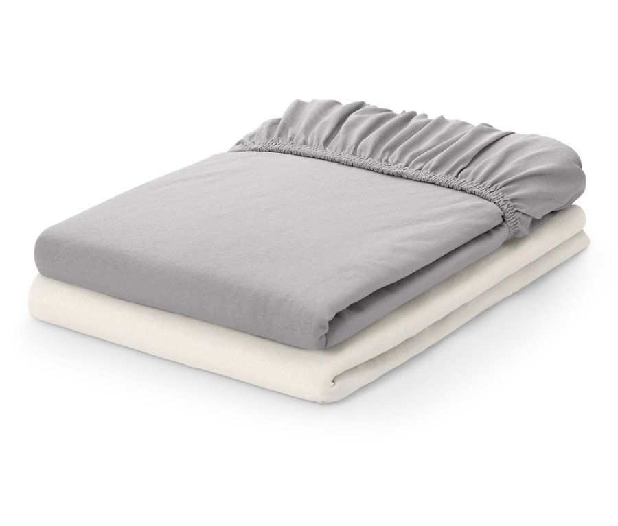 Dwa złożone prześcieradła z gumką: szare i kremowe.