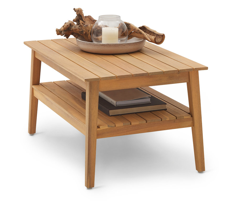 Jasnobrązowy drewniany stolik kawowy z dwiema półkami. Na górnej półce stoi miska ze świecą i drewnem dryfującym, na dolnej półce leżą książki.