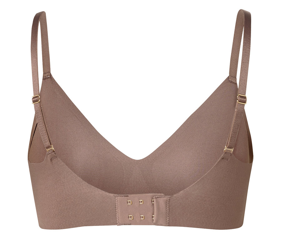 Zbliżenie beżowego biustonosza z regulowanymi ramiączkami i zapięciem na haftki z tyłu.