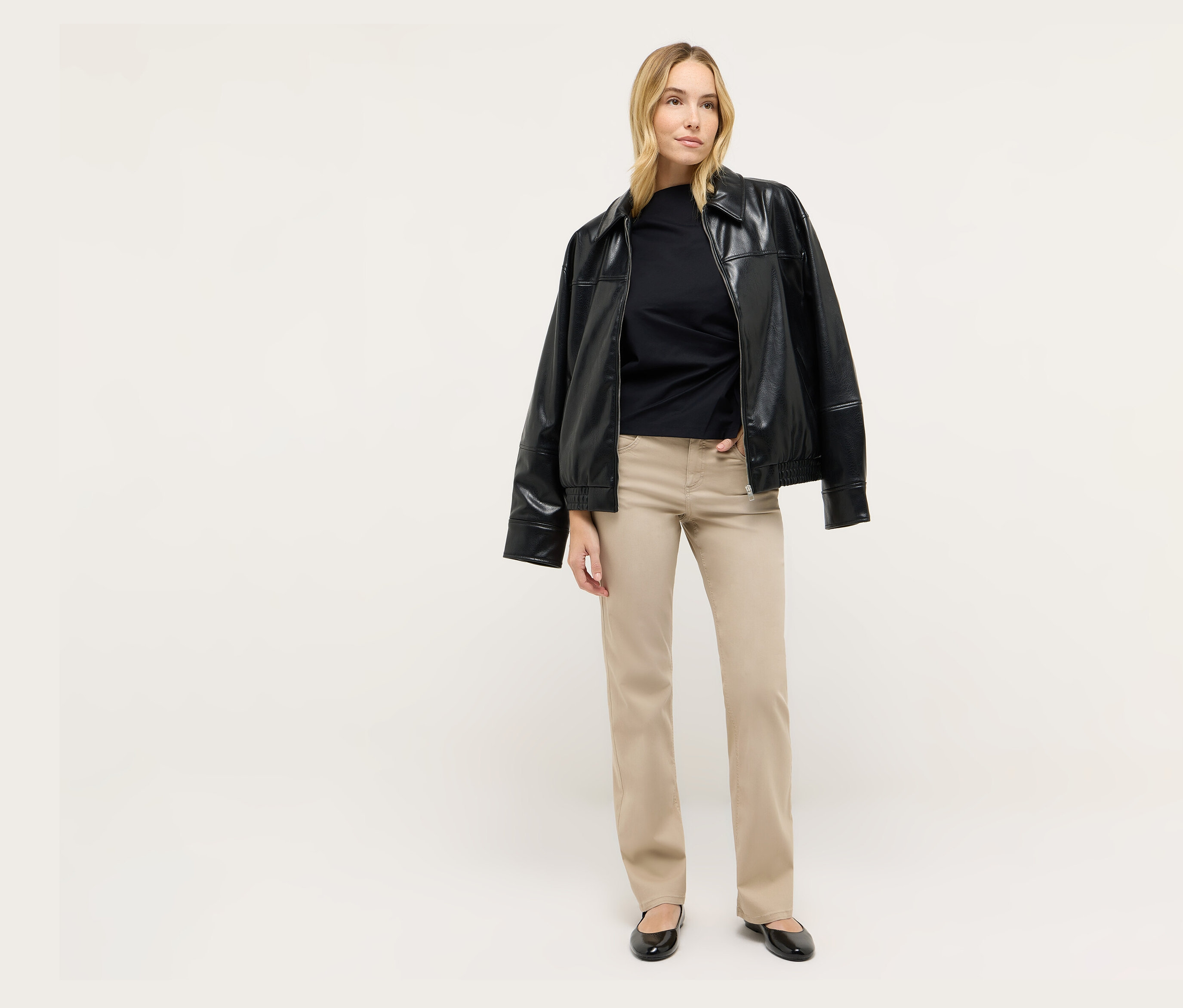 Blondwłosa kobieta stoi, ma na sobie czarną kurtkę i dżinsy Angels „Lara”, Straight Fit.