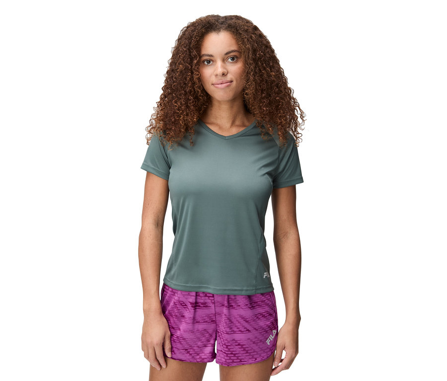 Kobieta o kręconych włosach ma na sobie szarą koszulkę i różowe szorty.