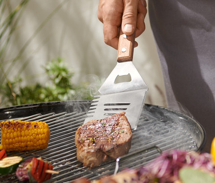 Mężczyzna grilluje stek za pomocą narzędzia wielofunkcyjnego do grillowania.