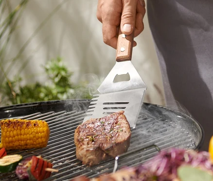 Mężczyzna grilluje stek za pomocą narzędzia wielofunkcyjnego do grillowania.