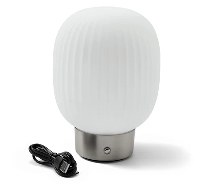 Lampa stołowa LED z akumulatorem i szklanym kloszem stoi obok czarnego kabla ładującego.