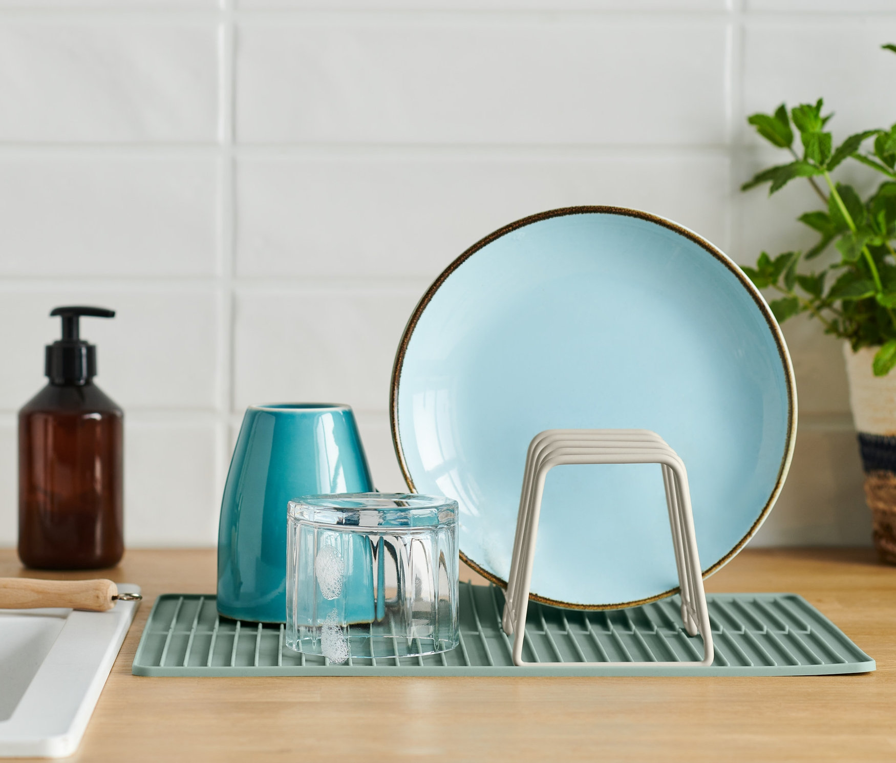 Na blacie kuchennym znajduje się suszarka do naczyń z talerzem, szklanką i wazonem.