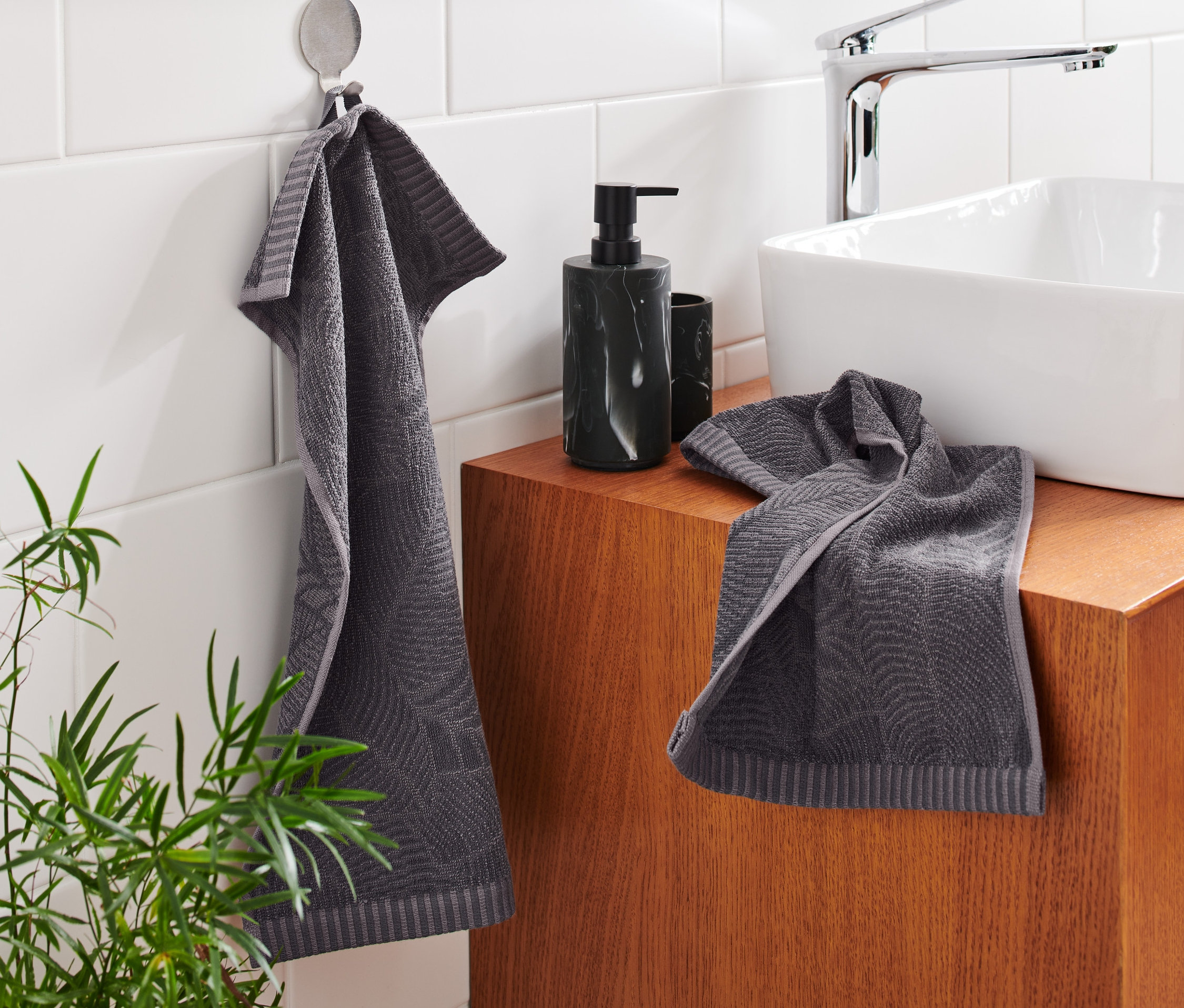 W łazience wiszą i leżą dwa żakardowe ręczniki dla gości.