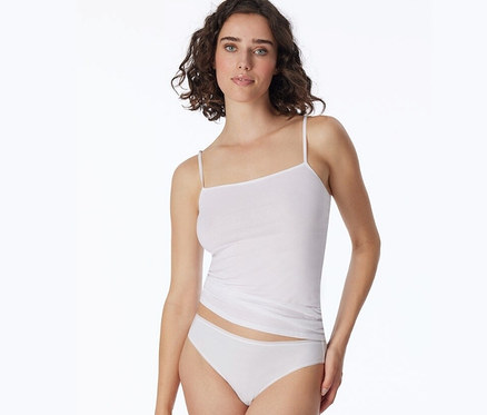 Kobieta ma na sobie biały top i figi mini z bawełną ekologiczną SCHIESSER, 2 pary, białe.