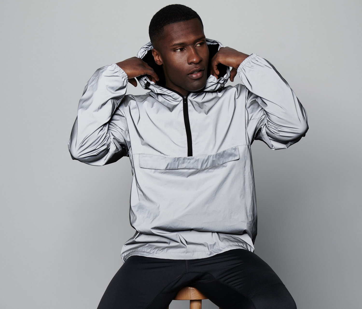 Mężczyzna siedzi na stołku i zakłada odblaskową kurtkę wiatrówkę.