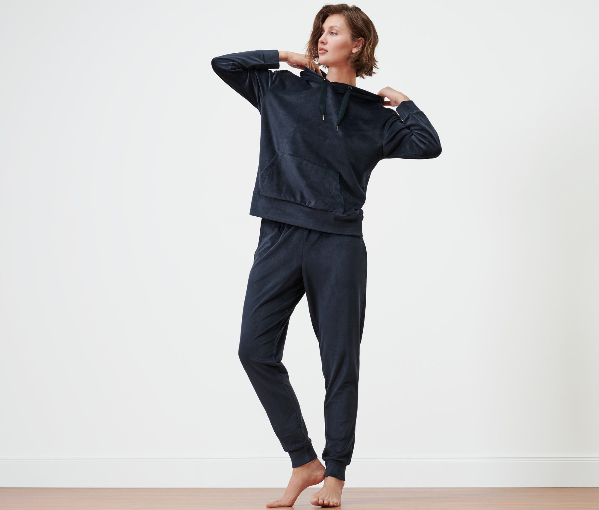 Kobieta poprawia kaptur dresu domowego z weluru.