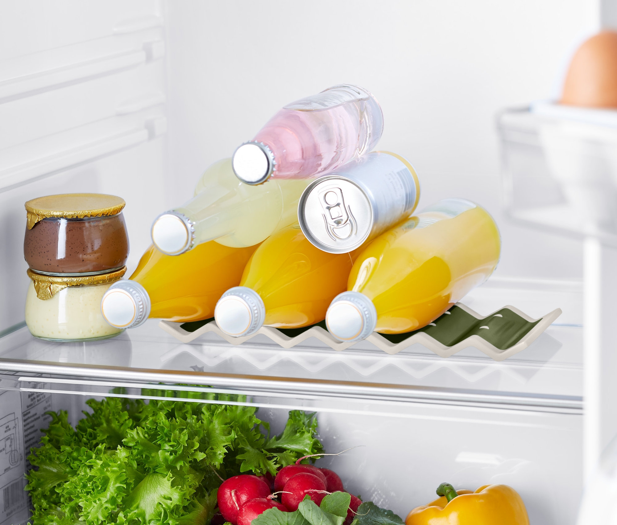W lodówce znajdują się dżemy, napoje w stojaku na butelki do lodówki, warzywa i jajka.