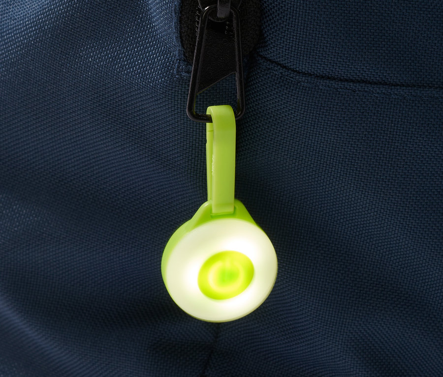 Zielona przywieszka LED, 3 sztuki, wisi na zamku błyskawicznym niebieskiej torby.
