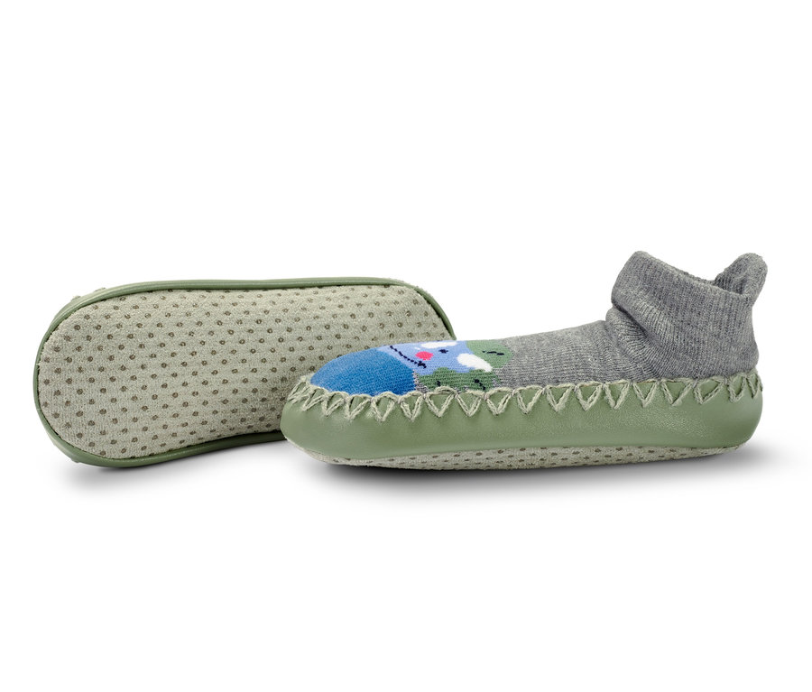 Dwie pary skarpeto-kapci dziecięcych: jedna szara z motywem dinozaura, a druga z jasnozieloną podeszwą.