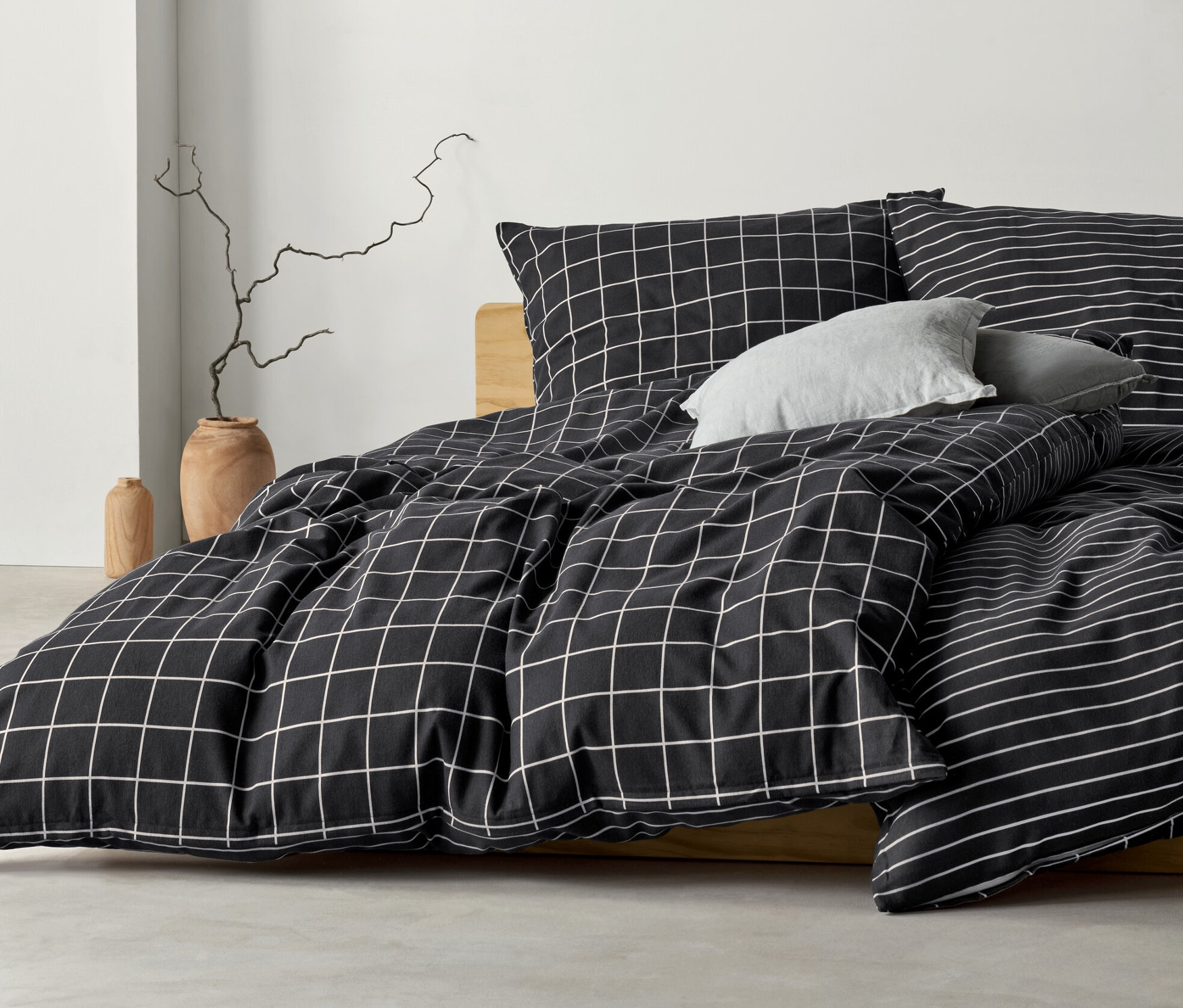 Antracytowa pościel flanelowa w kratę i paski na łóżku.