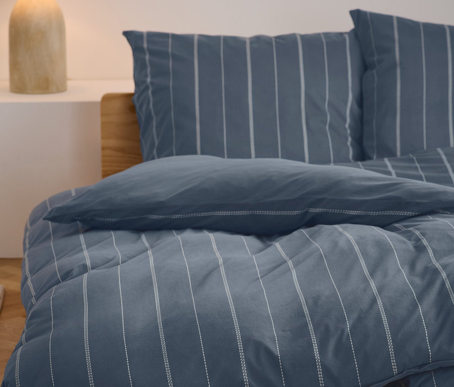 Pościel z zimowego dżerseju w rozmiarze standardowym i niestandardowym z niebiesko-białym wzorem w paski na łóżku.