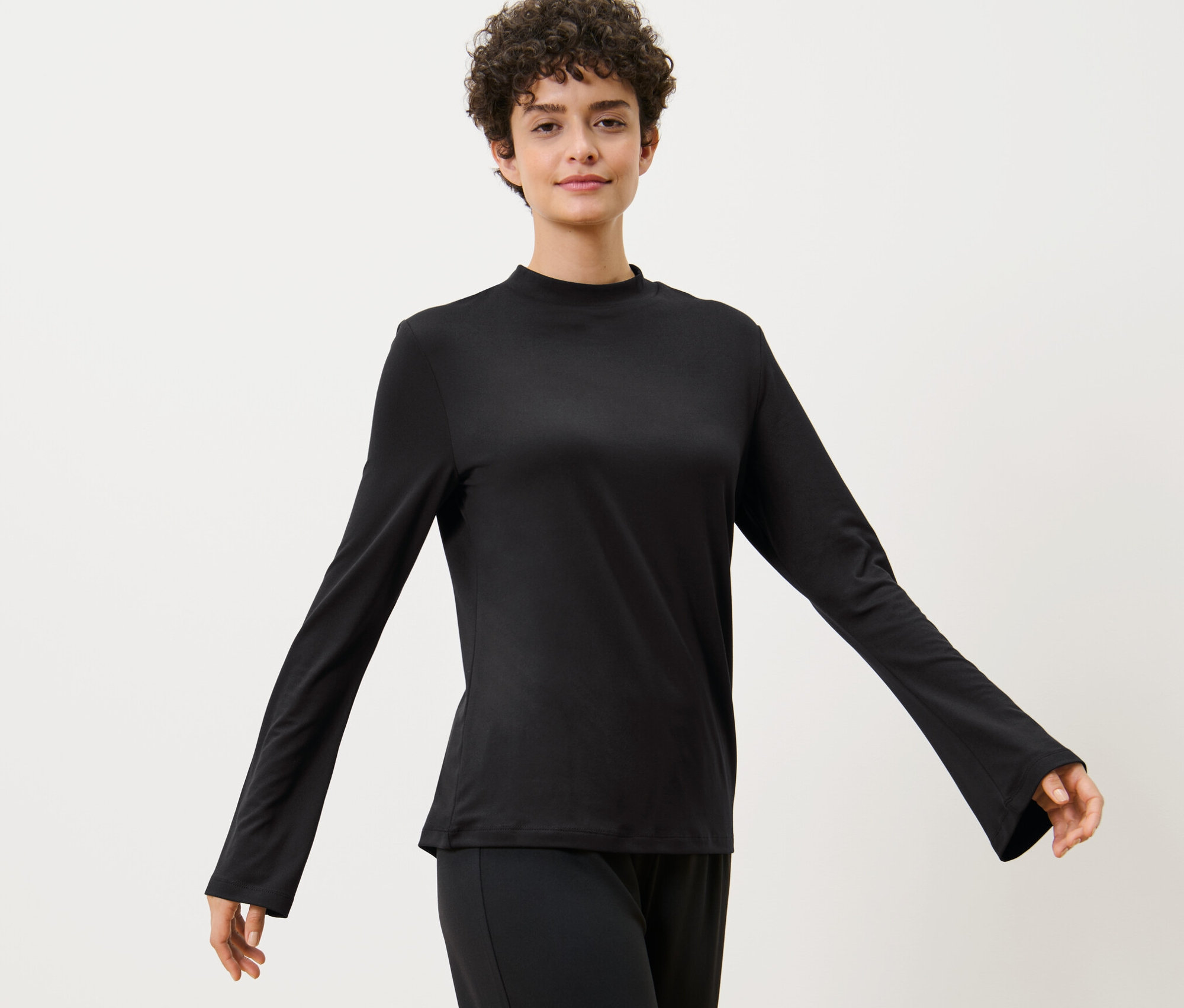 Kobieta pozuje w koszulce sportowej z długim rękawem.