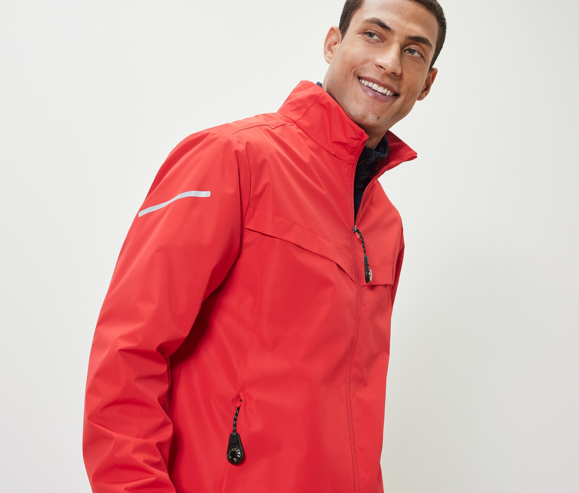 Mężczyzna w czerwonej kurtce z 2 zawieszkami na zamek błyskawiczny.