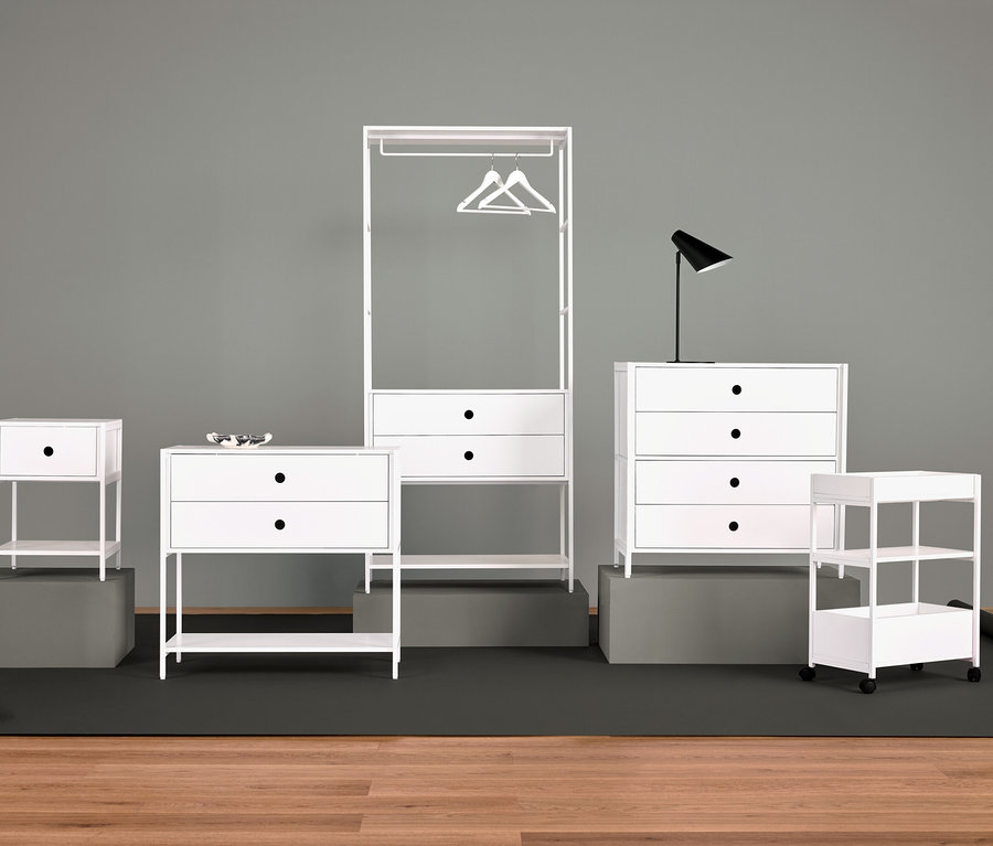 Aranżacja białych mebli z szafką nocną, komodą z szufladami, wieszakiem na ubrania, lampą i półkami.