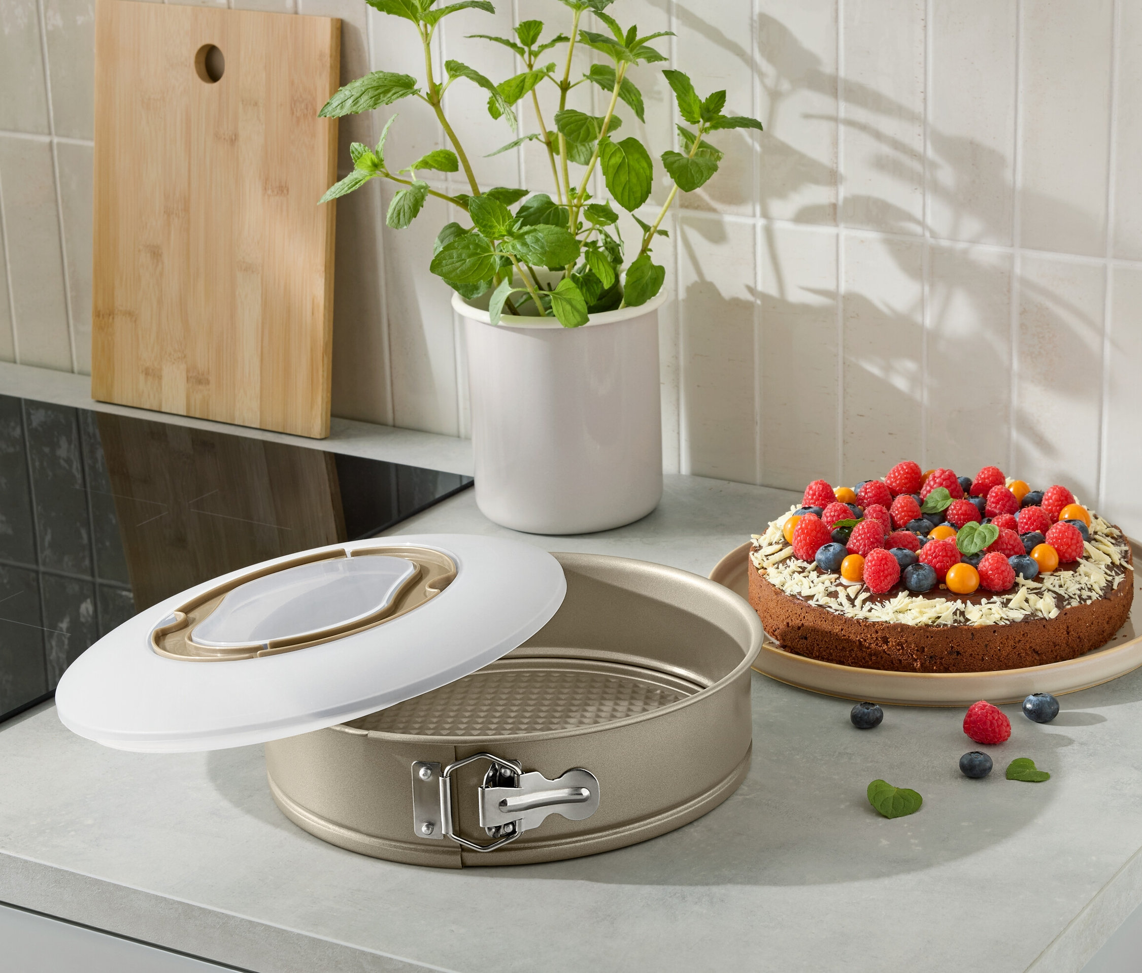 Otwarta forma do ciasta z upieczonym ciastem udekorowanym owocami na blacie kuchennym.