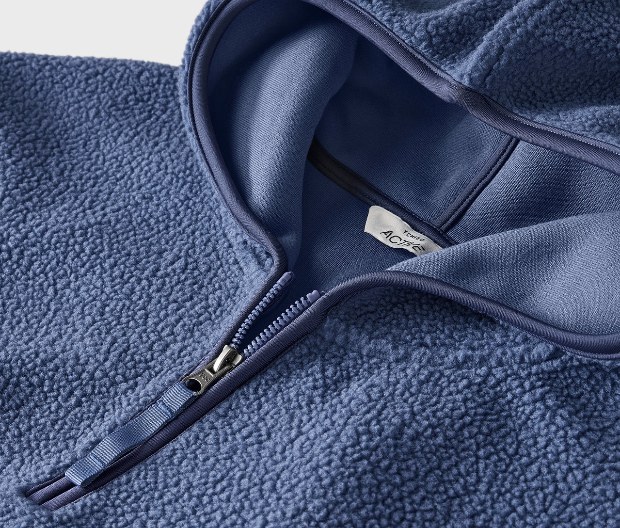 Zbliżenie na niebieską bluzę polarową z kapturem i zamkiem błyskawicznym.