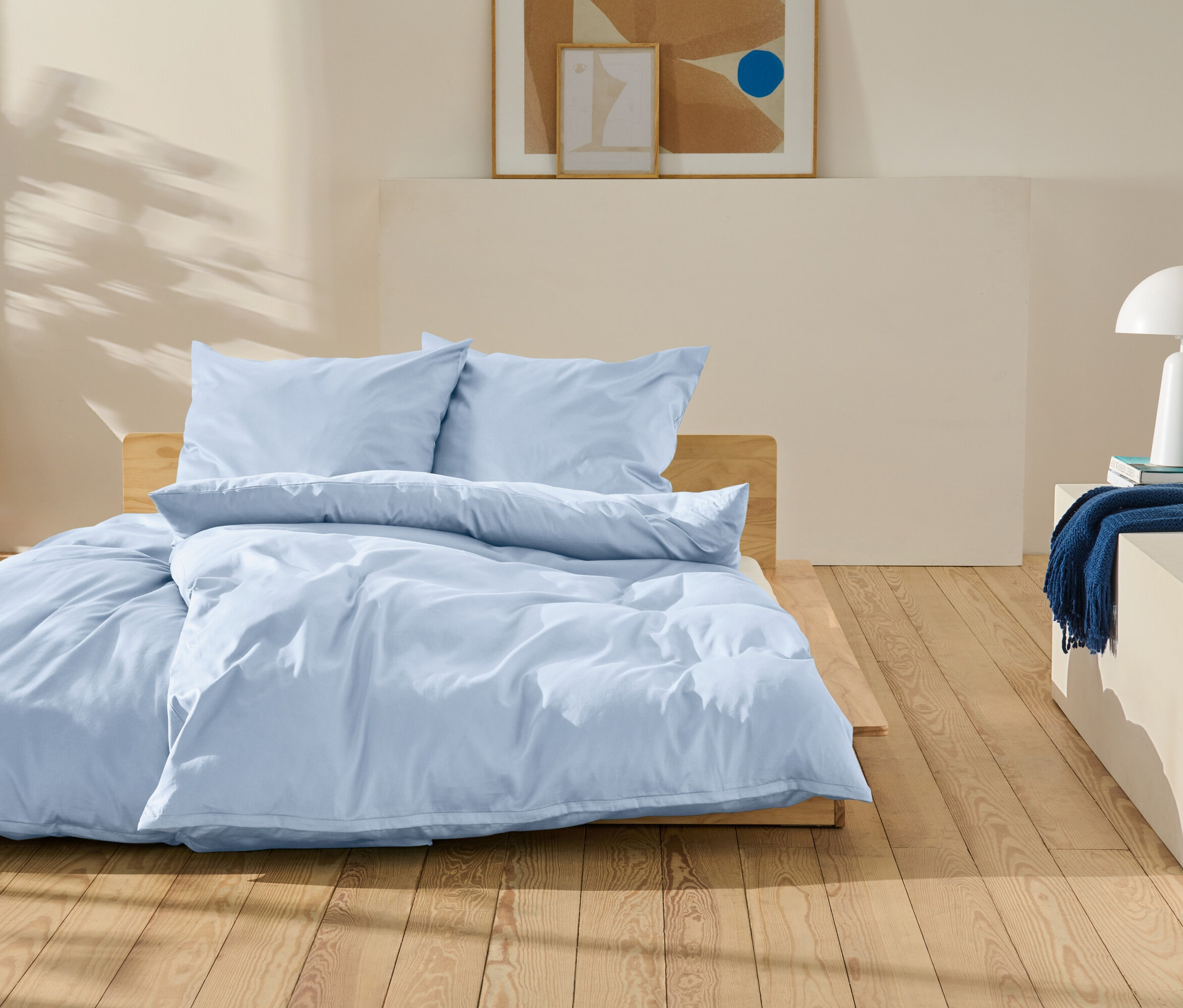 Jasnoniebieska pościel na drewnianym łóżku w sypialni.
