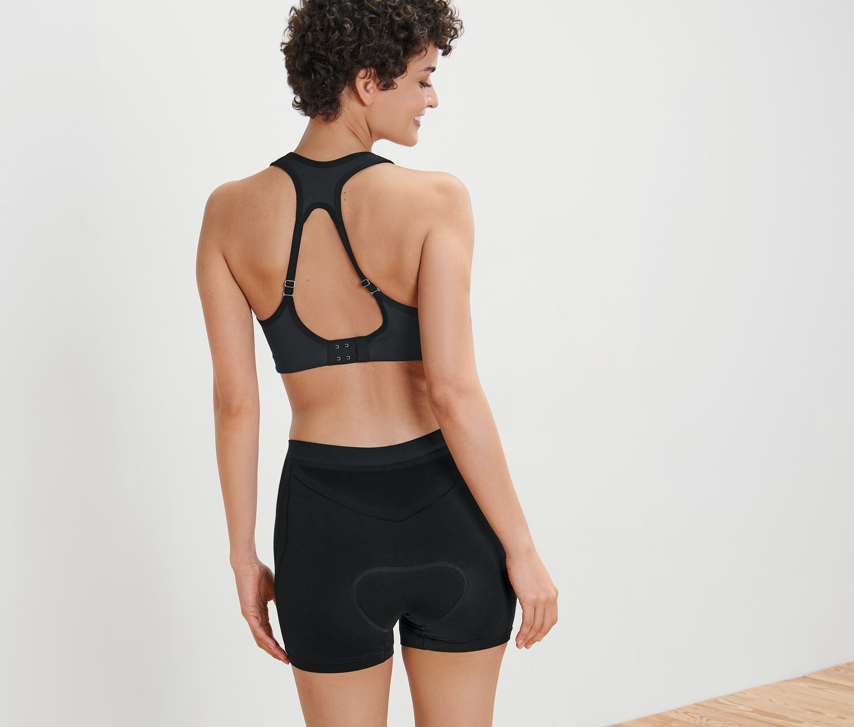 Kobieta ma na sobie biustonosz sportowy i bokserki rowerowe.