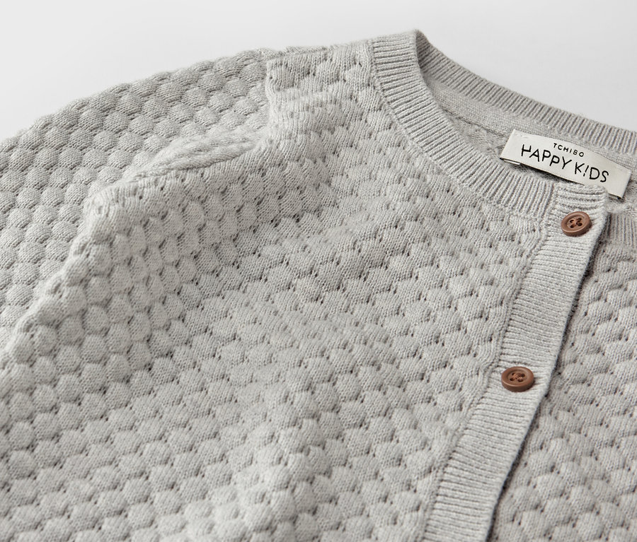 Zbliżenie na szary rozpinany sweter dziecięcy.