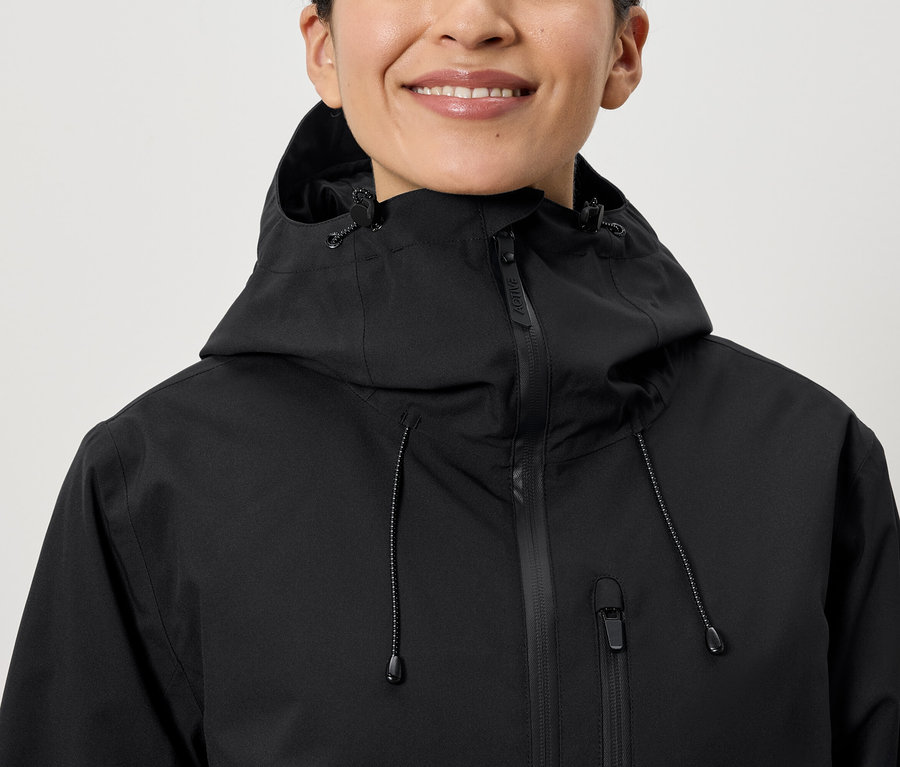 Uśmiechnięta kobieta ma na sobie czarną kurtkę z kapturem.