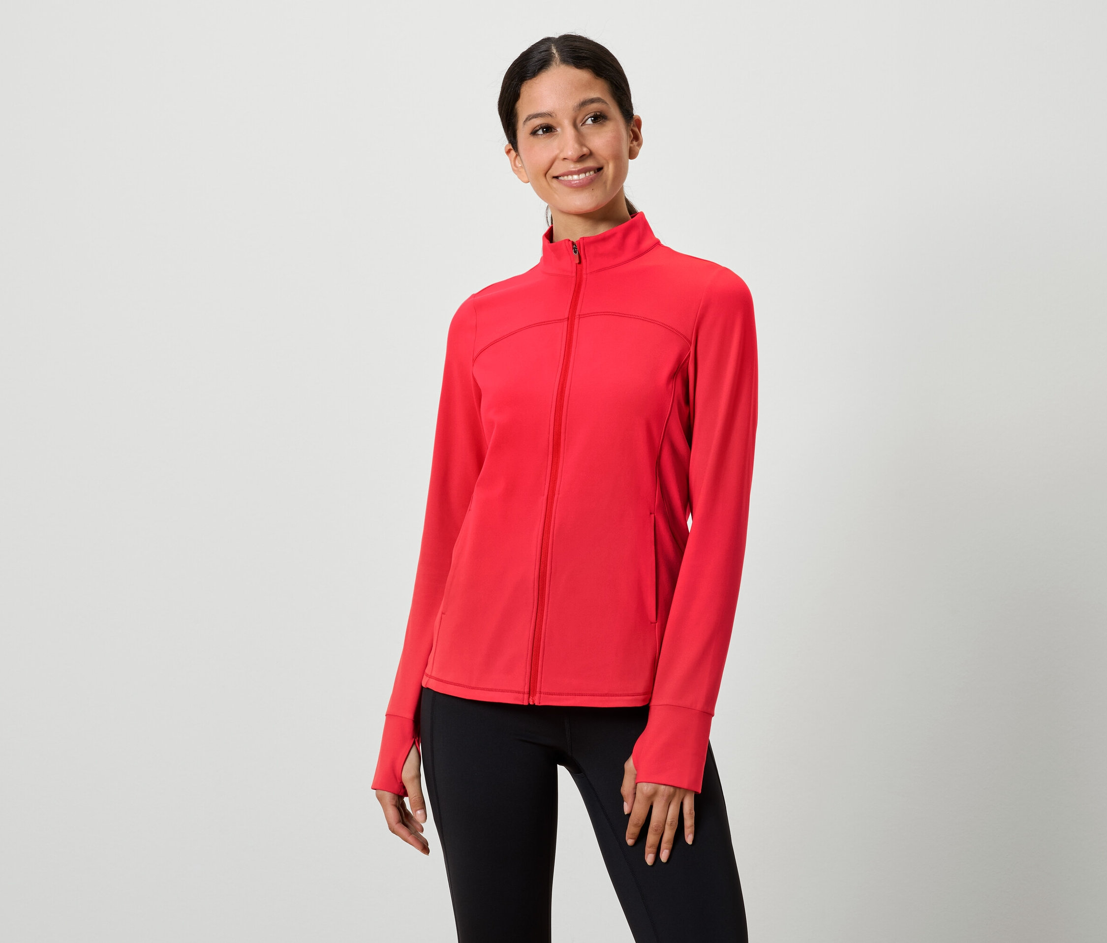 Kobieta ma na sobie czerwoną bluzę z zamkiem i czarne legginsy.