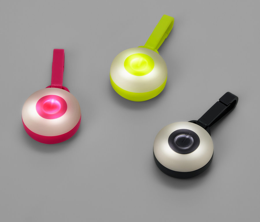 Trzy okrągłe lampki z klipsami w kolorach różowym, zielonym i czarnym na szarym tle.