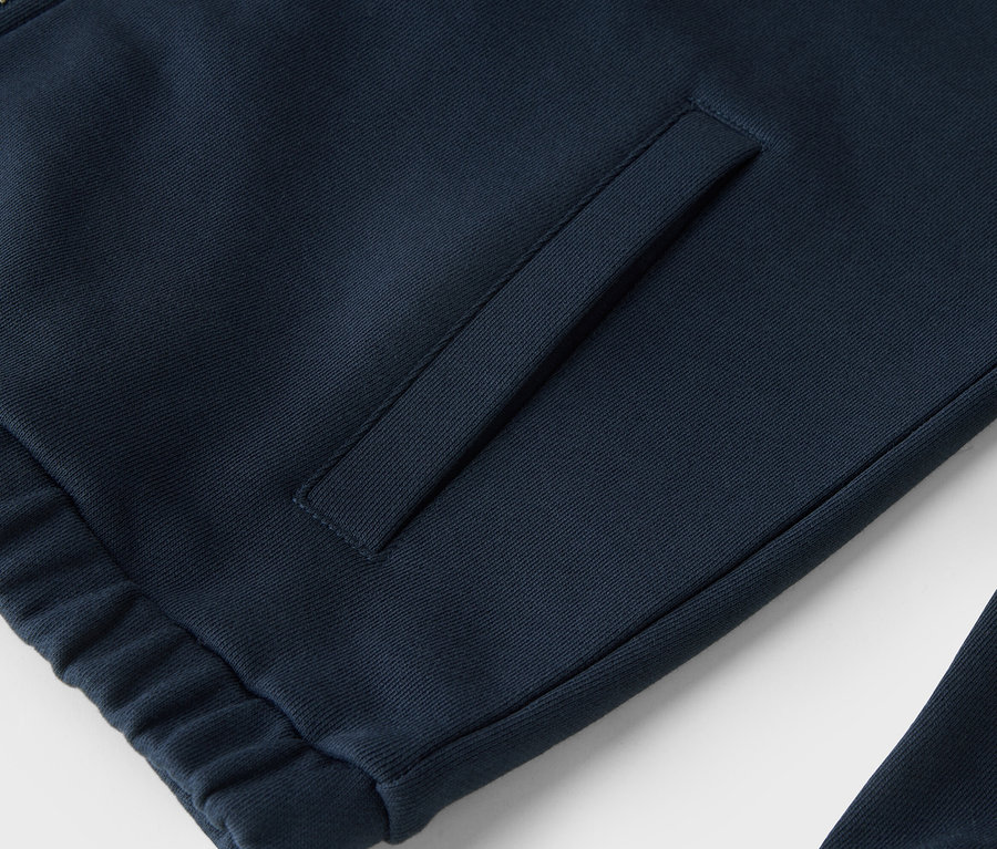 Zbliżenie na granatową bluzę dresową z zamkiem błyskawicznym i kieszenią.