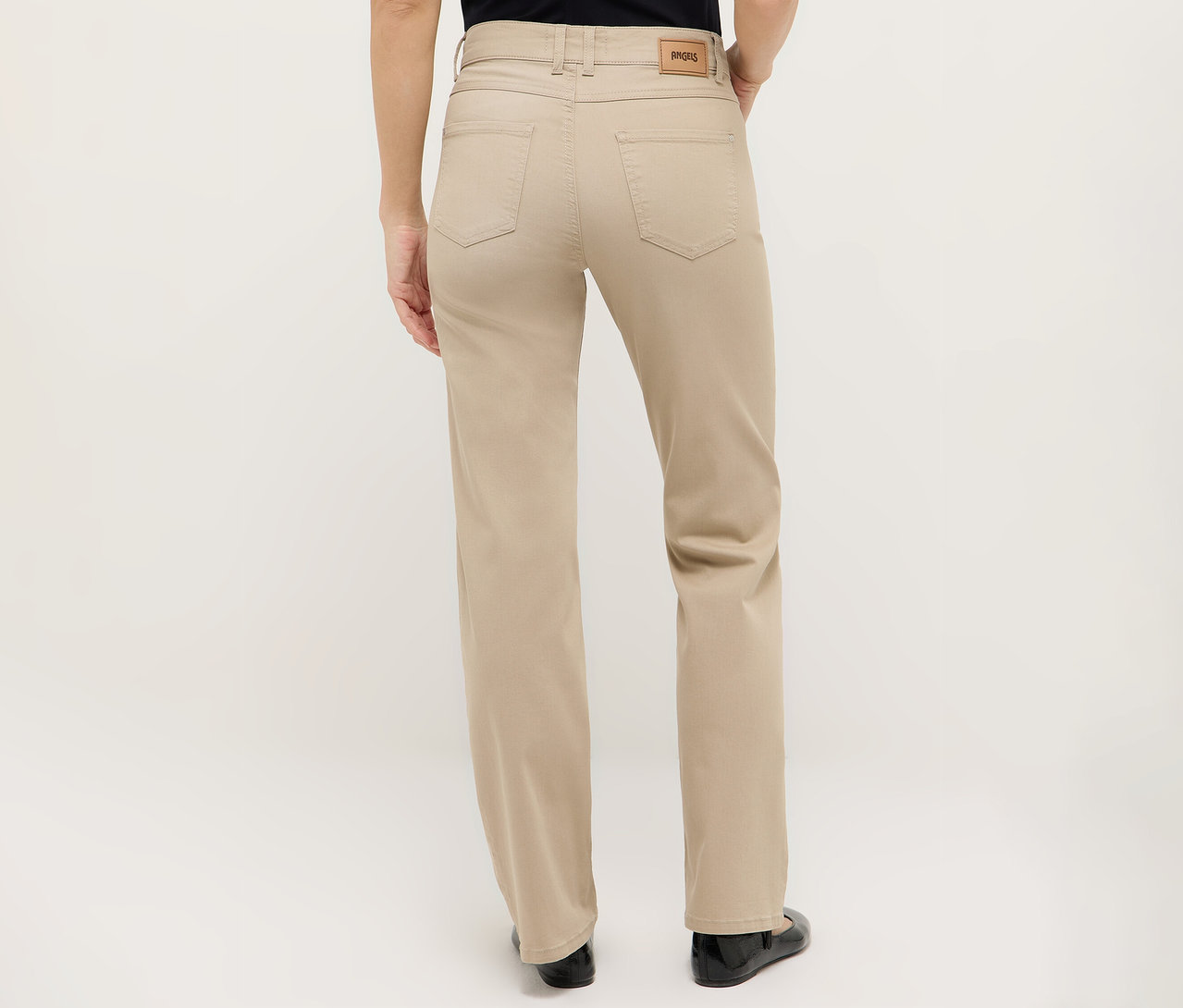 Widok z tyłu kobiety ubranej w beżowe spodnie i czarne buty.