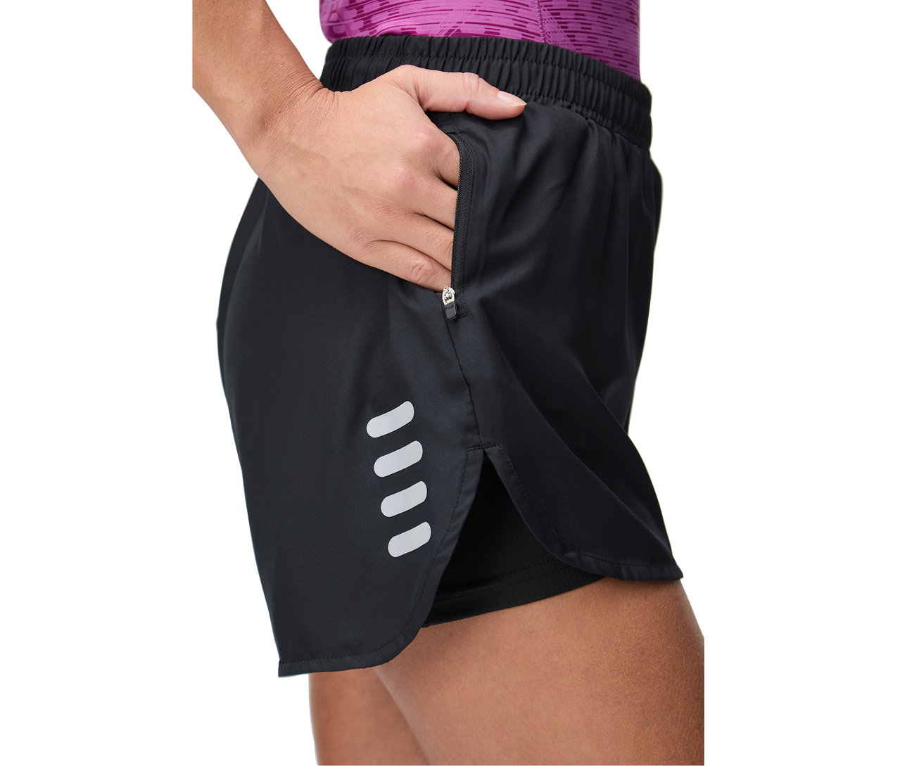 Kobieta sięga do kieszeni na zamek błyskawiczny w czarnych spodenkach z odblaskowymi paskami.