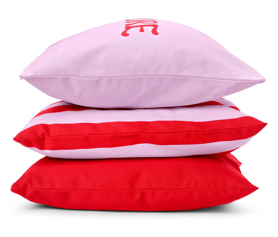 Ułożone są trzy poduszki: różowa poduszka z napisem, czerwono-biała poduszka w paski i czerwona poduszka.