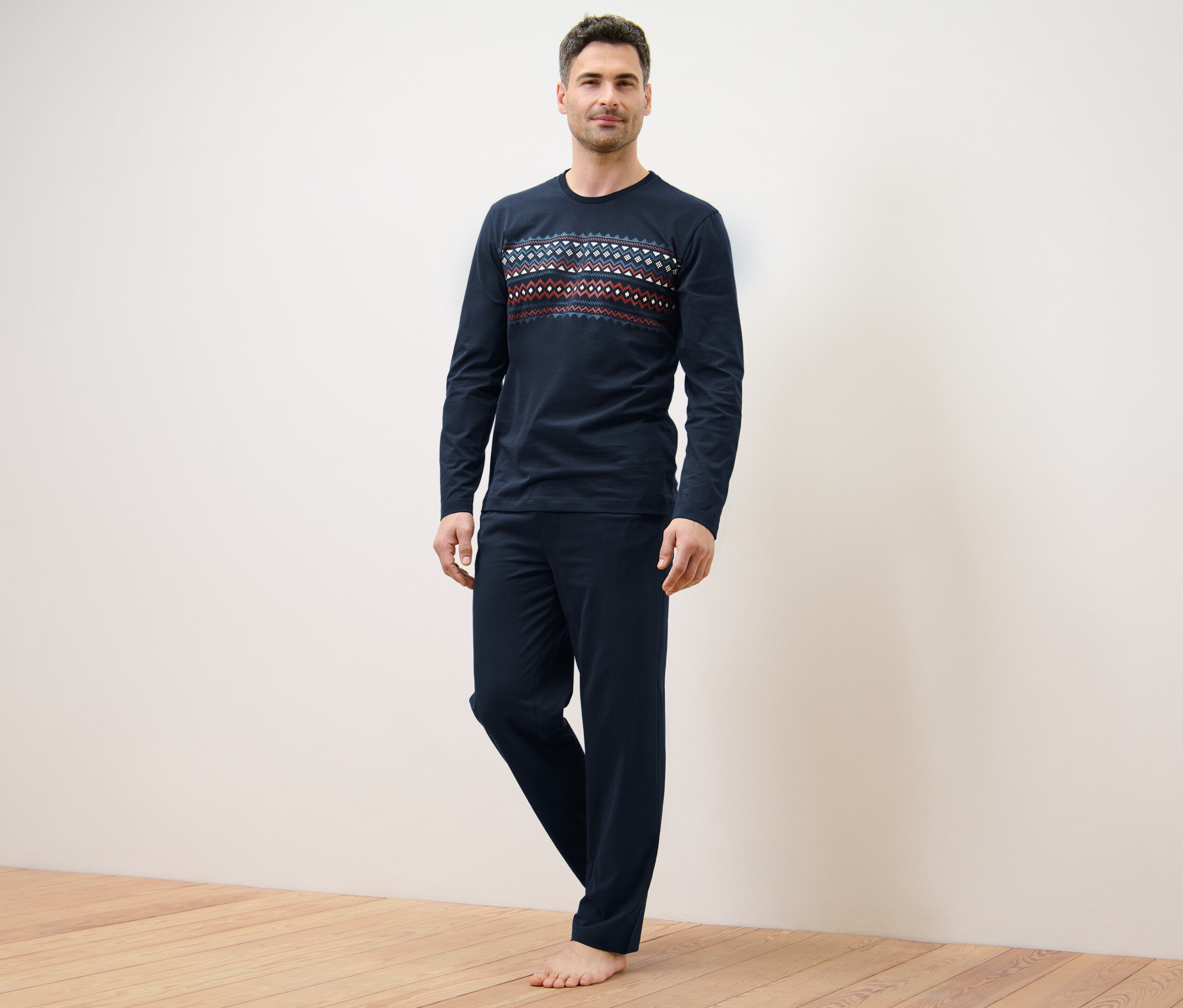 Mężczyzna stoi w granatowej piżamie.