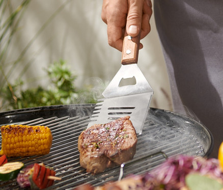 Mężczyzna grilluje stek za pomocą narzędzia wielofunkcyjnego do grillowania.