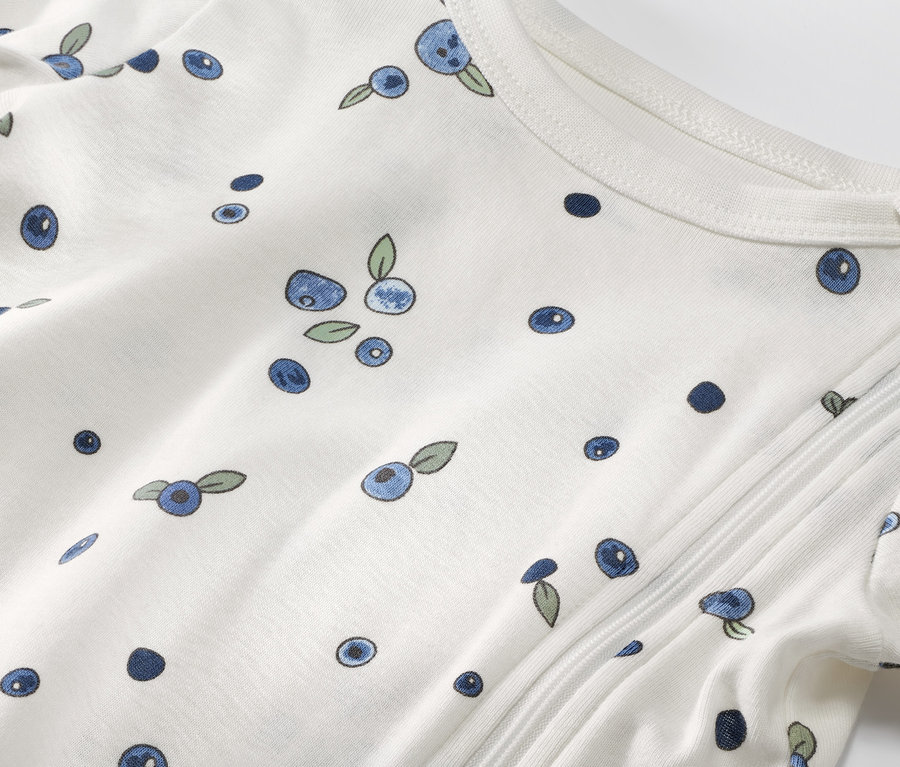 Zbliżenie na piżamę dziecięcą z 3-częściowego zestawu Piżamy dziecięce, 3 komplety, kolor jagodowy, z nadrukiem jagód.