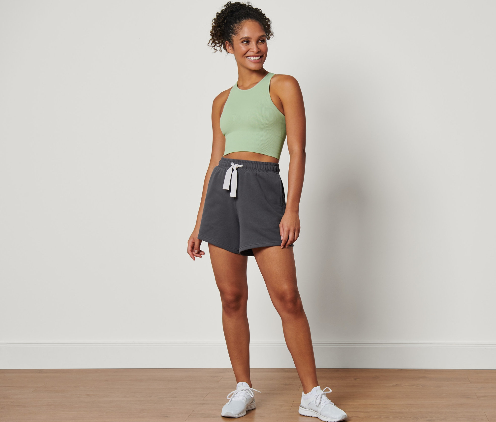 Kobieta stoi i ma na sobie szare sportowe szorty dresowe.